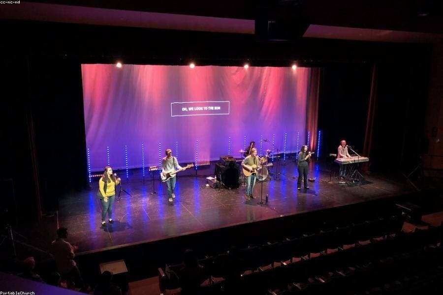 A worship team ministering on a brightly lit stage.